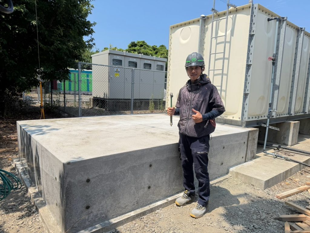 完成した受水槽コンクリート基礎と施工担当スタッフ
